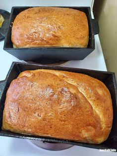 two loafs of bread sitting in black pans on top of a white counter