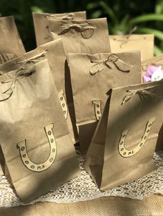 brown paper bags with horseshoes on them sitting on a lace tablecloth covered table