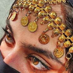 a close up of a person with gold jewelry on their head and eyes covered by a veil