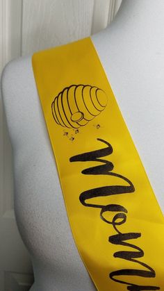 a yellow neck tie with black writing on the front and bottom, sitting on a mannequin's head