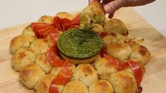 a person dipping something in a small bowl on top of some breaded buns