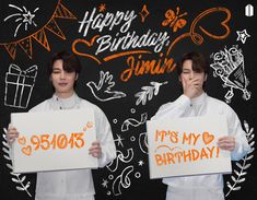 two young men holding up signs in front of a chalkboard with happy birthday written on it