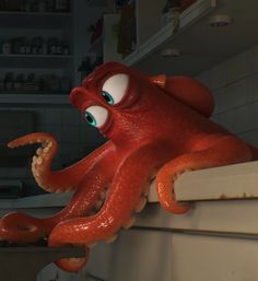 an octopus sitting on top of a kitchen counter next to a sink with green eyes