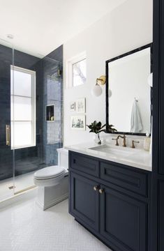 a white and black bathroom with a toilet, sink, shower stall and large mirror