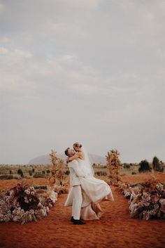 a bride and groom hugging in the desert