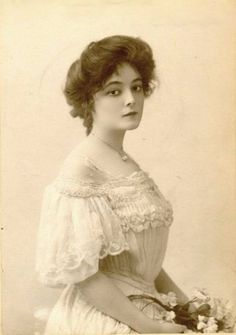 an old photo of a woman in a dress with flowers on her head and shoulders