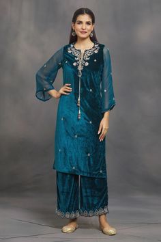 Caribbean sea blue velvet kurta with multi colored floral aari and zardozi embroidery. Comes with pant.
Components: 2
Pattern: Embroidered
Type Of Work: Aari and Zardozi Hand Work
Neckline: Notched
Sleeve Type: Three Quarter
Fabric: Velvet
Color: Blue
Other Details: 
Tasseled neckline
Occasion: Puja - Aza Fashions Festive Designer Pant Set With Mirror Work, Festive Velvet Long Sleeve Sets, Festive Velvet Straight Kurta, Bollywood Festive Pant Set With Mirror Work, Festive Bollywood Pant Set With Mirror Work, Bollywood Velvet Sets With Long Sleeves, Designer Velvet Kurta For Diwali, Semi-stitched Velvet Kurta With Dabka Work, Velvet Straight Kurta With Zari Work