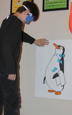 a young boy standing in front of a drawing of a penguin with an orange beak