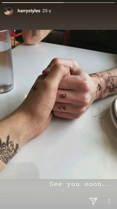 two people sitting at a table with their hands on each other's wrist, holding hands