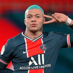 a soccer player with blue hair is making the peace sign while wearing a red, white and blue shirt