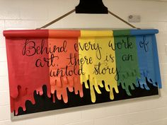 a rainbow banner hanging on the wall with words written in different colors and saying behind every work of art there is an unto story