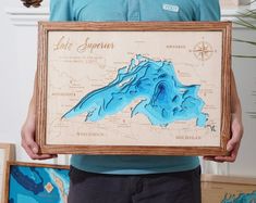 a person holding up a framed map of lake stupenness