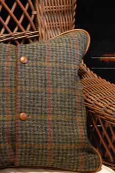 a plaid pillow sitting on top of a wooden chair next to a wicker basket