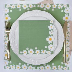 a place setting with flowers and green napkins