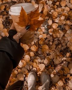 a person holding a coffee cup with a leaf on it's wrapper in front of their face