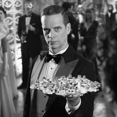 a man in a tuxedo holding a platter of food