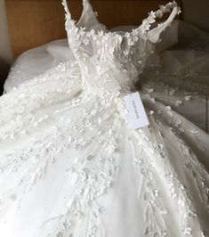 a white wedding dress is displayed on a bed