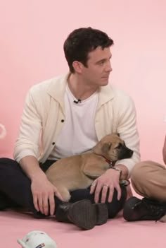 two people sitting on the floor with a dog