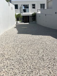 an empty driveway in front of a white house