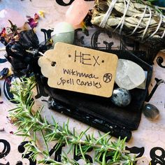 an assortment of rocks and plants on a table with a sign that says hey, witchma's spell cards