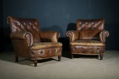 two brown leather chairs sitting on top of a carpeted floor next to each other