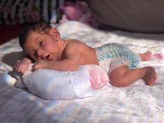 a baby laying on top of a white blanket