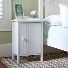 a small white cabinet next to a bed