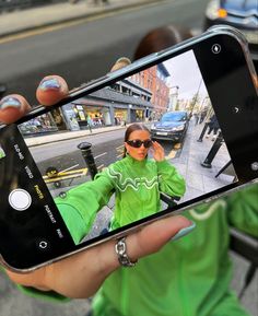 a person holding up a cell phone to take a selfie with the camera on their left hand