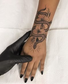 a woman's hand with a tattoo on it and a snake wrapped around the wrist