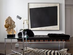 a living room with a zebra print rug and glass coffee table in front of a painting on the wall