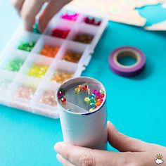 a person is holding a cup with beads in it and some other items on the table