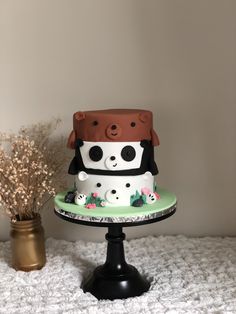 a three tiered cake with panda bears on top and flowers in the bottom corner