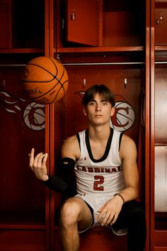 a young man sitting on top of a locker holding a basketball