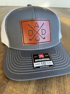 a gray and white trucker hat with a leather patch on the front that says, dad