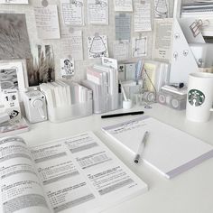 a white desk topped with lots of office supplies and paper on top of each other