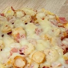 a pizza covered in cheese and meat sitting on top of a wooden table