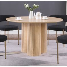 a round wooden table with black chairs around it and flowers in vases on top