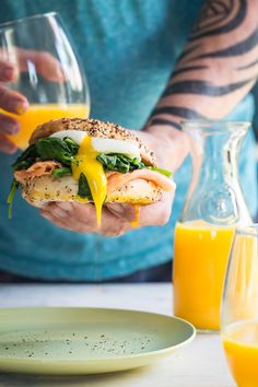 a person holding a sandwich with orange juice