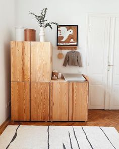 a wooden cabinet sitting on top of a hard wood floor next to a white rug