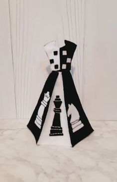 a black and white tie with chess pieces on the front, sitting on a marble surface