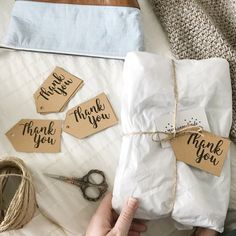 a person holding a gift wrapped in brown paper with thank you tags attached to it