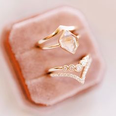 three different rings sitting on top of a pink velvet ring box, with one diamond in the middle