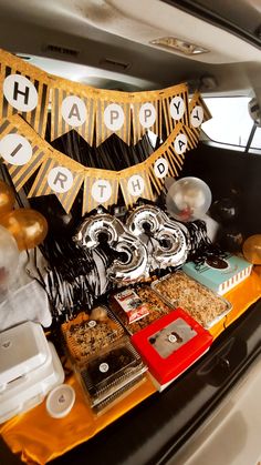 a birthday party in the back of a car with lots of food and decorations on it