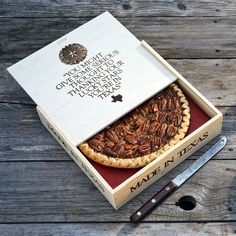 a pecan pie in a box with a knife next to it