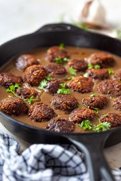 a pan filled with meatballs covered in gravy and garnished with parsley