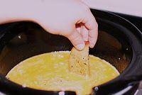 a person dipping tortilla chips into a bowl of soup