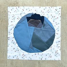 a quilted piece of fabric with blue and grey colors on it, in the middle of a square