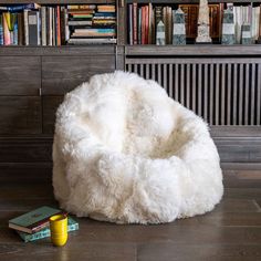 a white bean bag chair sitting on top of a wooden floor next to a book shelf