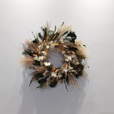 a dried wreath hanging on the wall in front of a white wall with no one around it