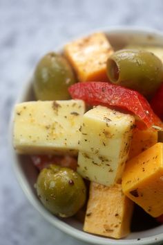 a bowl filled with different types of fruit and vegetables on top of a white table